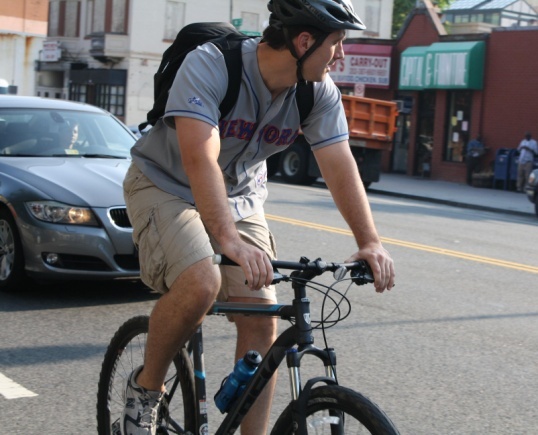 Man wearing helmet and bicycling in traffic