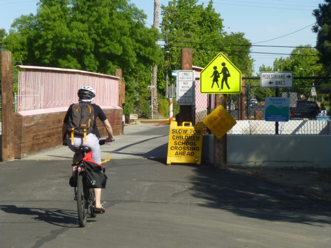 A bicyclist crossing on the bicycle-only bridge across Matadero Creek.